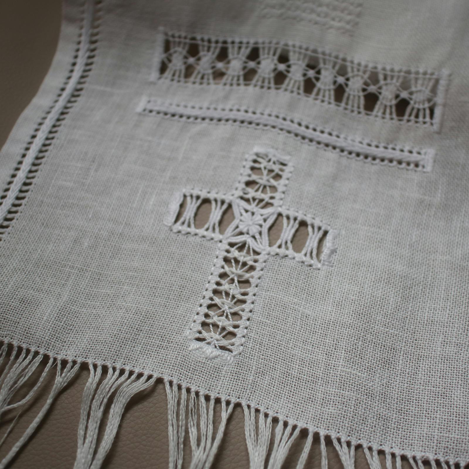 白のリネン生地にドロンワークで描かれた、繊細な十字架モチーフのサンプラー